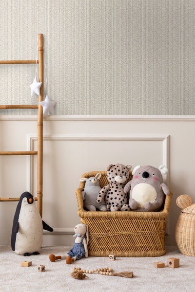 Kinderzimmer mit gemusterter Tapete, Wandpaneelen, Rattansessel mit Kuscheltieren, Bambusleiter, Pinguin und Holzspielzeug.