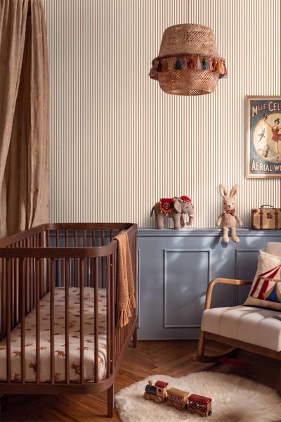 Ein Kinderzimmer mit gestreifter Tapete, einem hölzernen Kinderbett, einem Schaukelstuhl und Zirkusdekorationen im Vintage Stil.
