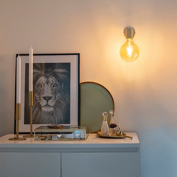 Dekoratives Interieur mit Wandleuchte und Wohnaccessoires auf einem Schrank