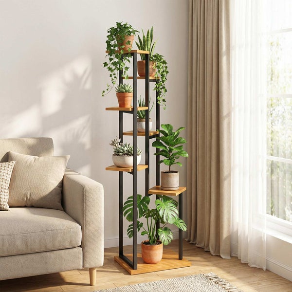 Moderne Pflanzensäule mit schwarzem Metallgestell und Holzregalen, bestückt mit verschiedenen Zimmerpflanzen in einem hellen Wohnzimmer.