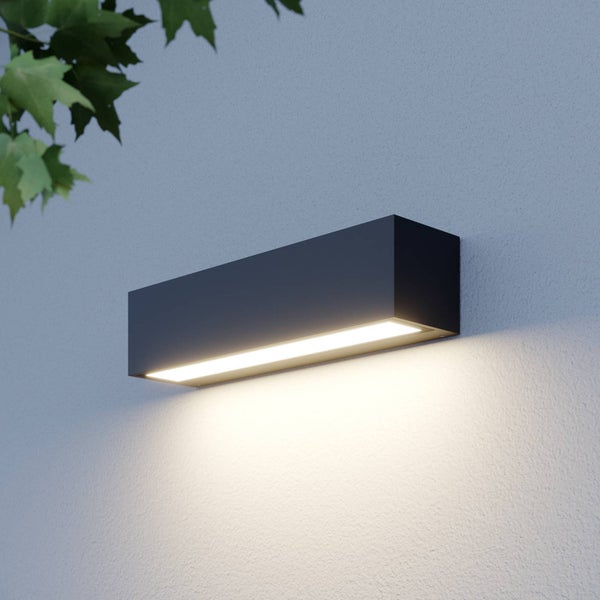 Moderne rechteckige Außenwandleuchte in Anthrazit an einer Hauswand montiert mit warmem Lichtaustritt nach unten.
