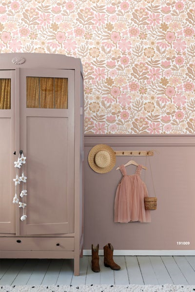 Helles Kinderzimmer mit floraler Tapete mit Blumenmuster in Rosa und Beige, weißem Schreibtisch und einem Kind auf einem Hocker.