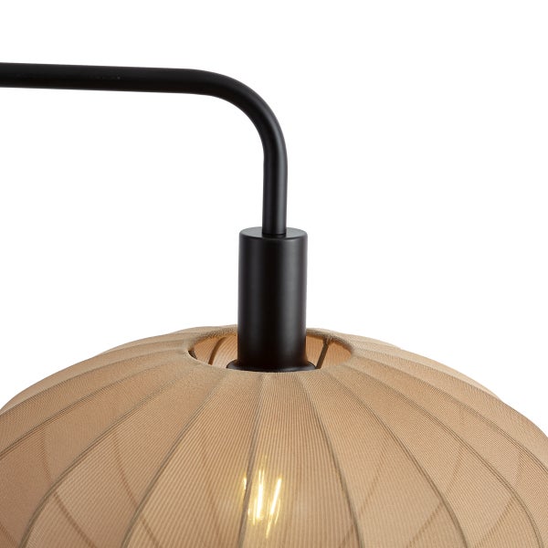 Nahaufnahme einer Leuchte mit schwarzem Metallarm und beige geripptem Stofflampenschirm.