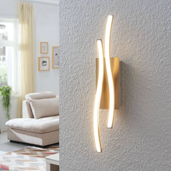 Moderne LED-Wandleuchte mit zwei geschwungenen, wellenförmigen Lichtelementen auf einem Metallfuß, montiert in einem hellen Wohnzimmer.