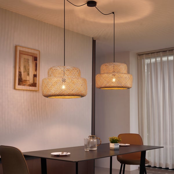 Zwei geflochtene Hängelampen aus Rattan über einem Esstisch