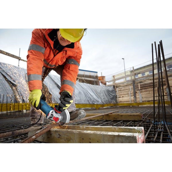 Ein Handwerker mit Schutzkleidung trennt mit einem Winkelschleifer Metallstangen auf einer Baustelle.