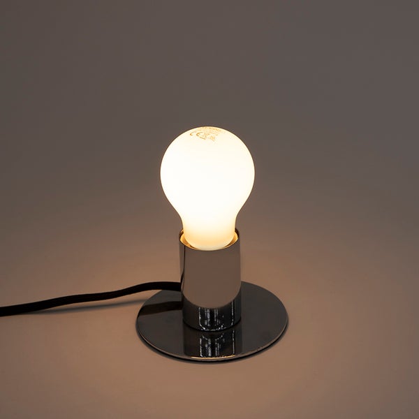 Tischleuchte aus glänzendem Metall mit eingeschaltetem Leuchtmittel.