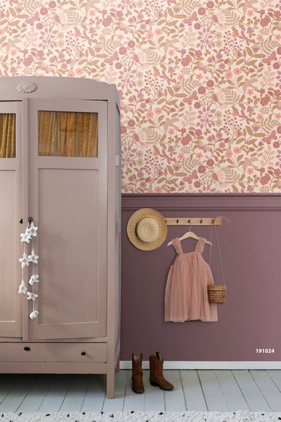 Hell gestaltetes Kinderzimmer mit floraler Vliestapete mit Vogel- und Schmetterlingsmotiven, einem Holzschrank und einer Garderobe mit Hut und Kleid.
