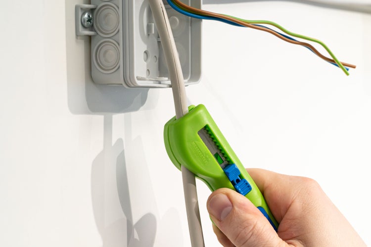 Aufputzverteilerdose mit Kabel und Kabelabisolierer in der Anwendung.