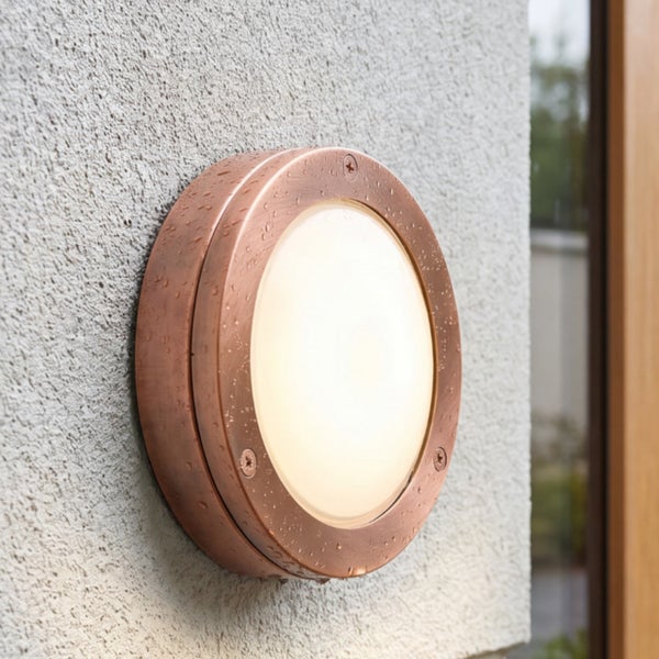 Runde Außenwandleuchte aus Metall in Kupferoptik mit mattem Glas, montiert an einer Außenwand.