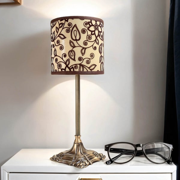 Tischleuchte mit floralem Muster und Brille auf einem Nachttisch