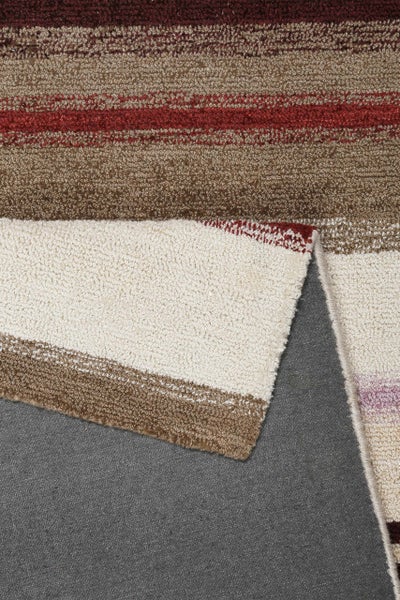 Gestreifter Teppich mit weichem Flor und umgeknickter Ecke zur Ansicht der Rückseite.