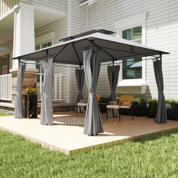 Moderner Gartenpavillon mit Metallgestell, Doppeldach und Vorhängen auf einer Holzterrasse neben einem Wohnhaus mit Gartenmöbeln.