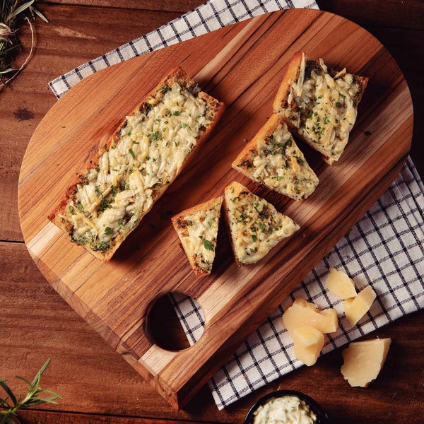 Brot mit Käse und Kräutern auf einem Holzbrett