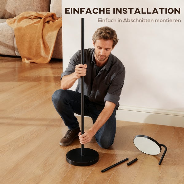 Mann montiert eine schwarze Stehlampe im Wohnzimmer. Einfache Installation.