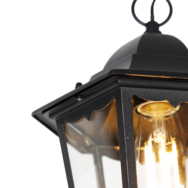 Detailansicht einer schwarzen Außenleuchte im Laternenstil aus Metall und Glas mit leuchtendem Leuchtmittel.