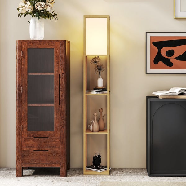 Moderne Stehleuchte aus hellem Holz mit integriertem Regal, platziert in einem hellen Wohnzimmer zwischen einem Holzschrank und einem Sideboard.