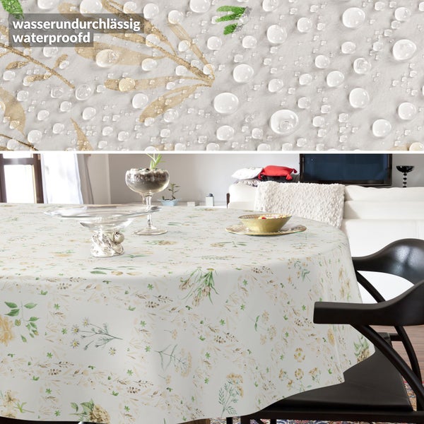 Runde, wasserundurchlässige Tischdecke mit Blumenmuster in einem hellen Wohnzimmer. Die Detailaufnahme zeigt Wassertropfen auf dem Stoff.