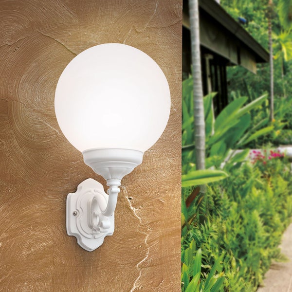 Klassische Außenwandleuchte mit weißer Glaskugel an einer strukturierten Wand in einem Garten.