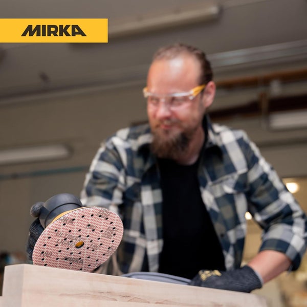 Handwerker schleift ein Holzwerkstück mit einem Mirka Exzenterschleifer und einer runden Schleifscheibe in einer Werkstatt.