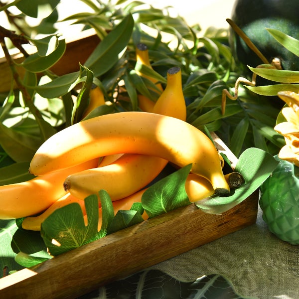 Dekorative gelbe Bananen in einer Holzschale mit Pflanzen