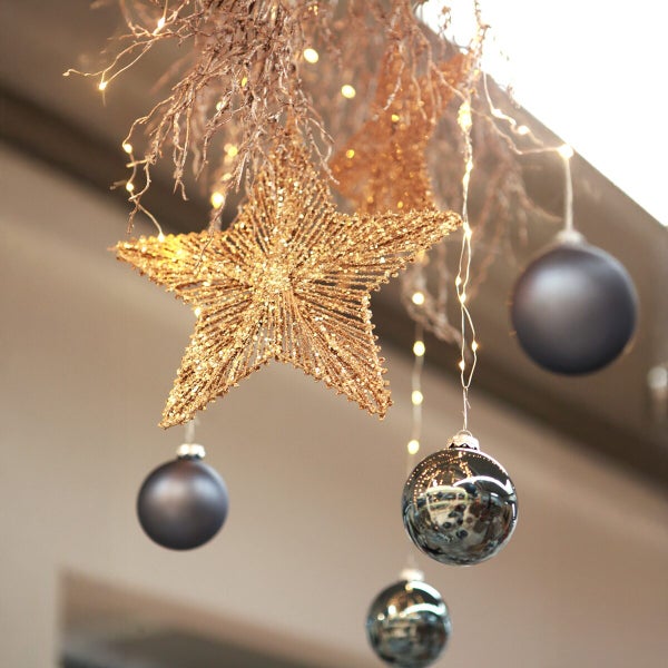 Weihnachtsdekoration hängend mit glitzerndem Stern, runden Christbaumkugeln und Lichterkette für die festliche Raumgestaltung.