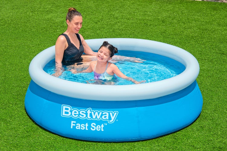 Rundes blaues Bestway Fast Set Aufblaspool mit weißem Luftring, darin eine Frau und ein Kind, auf einer Rasenfläche.