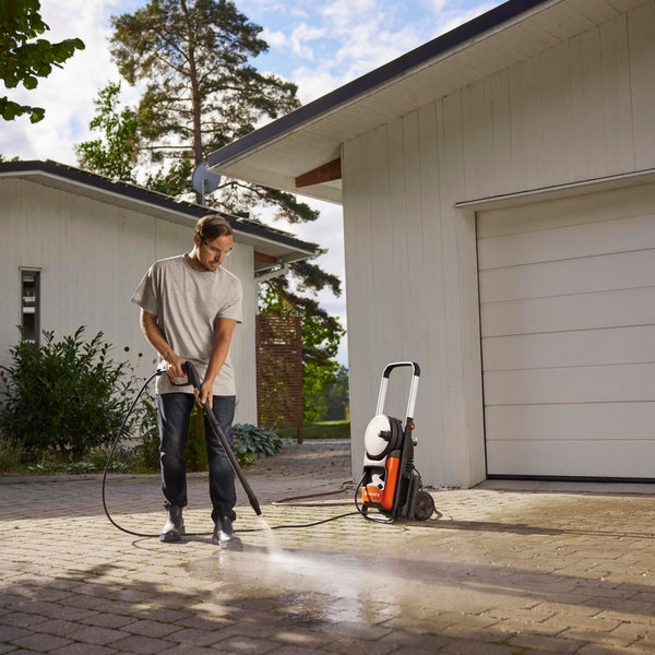 Mann reinigt Einfahrt mit Hochdruckreiniger vor Wohnhaus