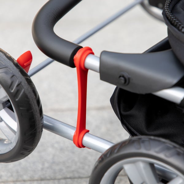 Detailansicht eines Kinderwagens mit schwarzem Griff, Reifen und rotem Befestigungselement