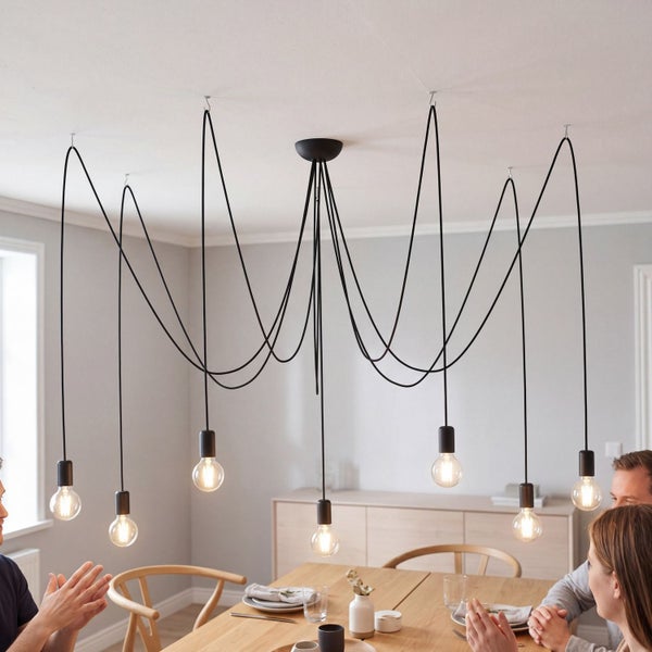 Mehrflammige schwarze Pendelleuchte im Spinnen-Design über einem Holztisch in einem hellen, modern eingerichteten Esszimmer.