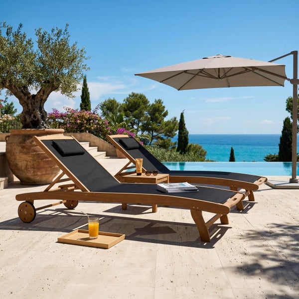 Zwei Sonnenliegen aus Holz mit schwarzer Bespannung auf einer hellen Terrasse neben einem Pool und einem Ampelschirm.