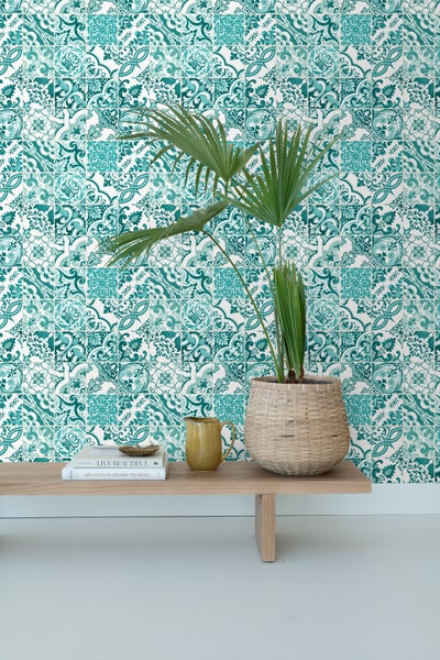 Wandgestaltung mit gemusterten Fliesen, Pflanze im Korb und Deko-Objekten auf einem Holztisch.