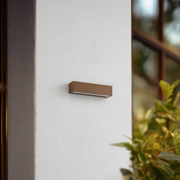 Rechteckige Außenwandleuchte in Braun, an einer Hauswand montiert, neben einer Pflanze.