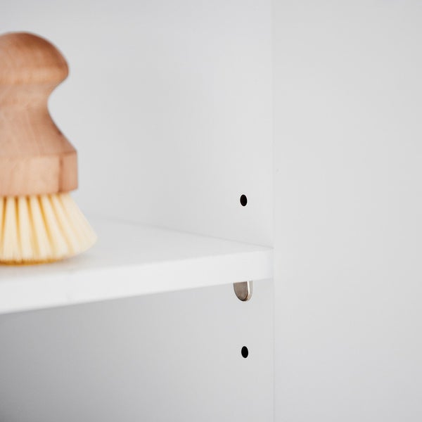Detailaufnahme eines Regals mit verstellbaren Fachböden und einer Bürste