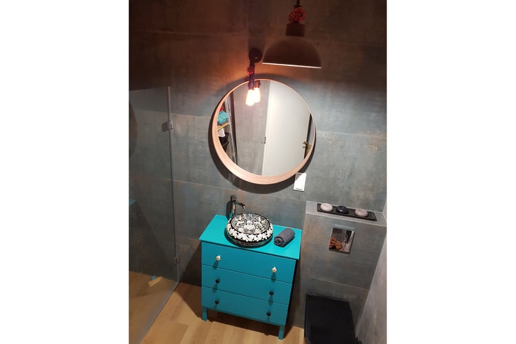 Badezimmer mit rundem Spiegel, Aufsatzwaschbecken und blauem Waschtisch
