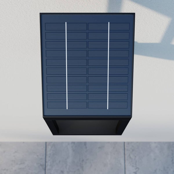 Draufsicht einer schwarzen Solar-Wandleuchte mit integriertem Solarpanel, montiert an einer Wand.