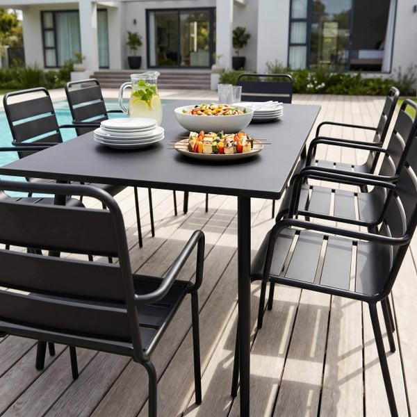 Modernes Gartenmöbel-Set mit schwarzem Metalltisch und Stühlen auf einer Holzterrasse am Pool.