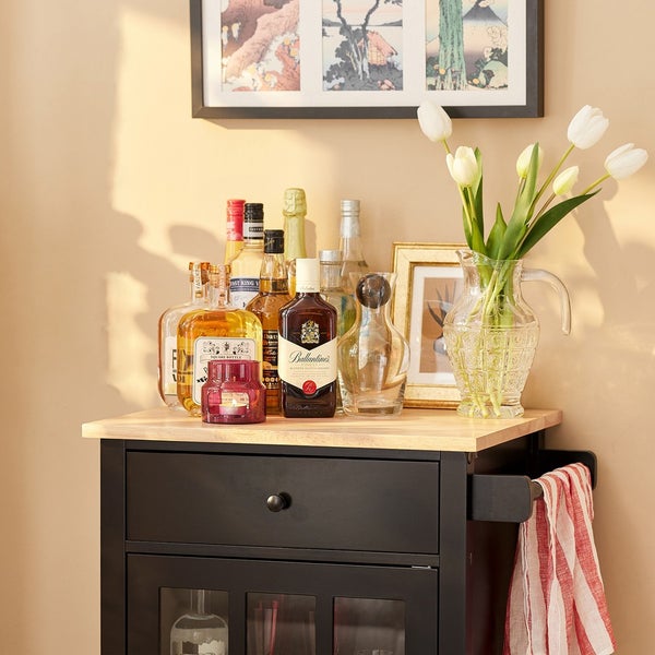 Barwagen mit Spirituosen, Glaswaren und Blumenvase dekoriert.