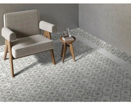 Moderner Wohnraum mit gemusterten Bodenfliesen und passender Sockelleiste, ausgestattet mit Sessel und kleinem Beistelltisch aus Holz.