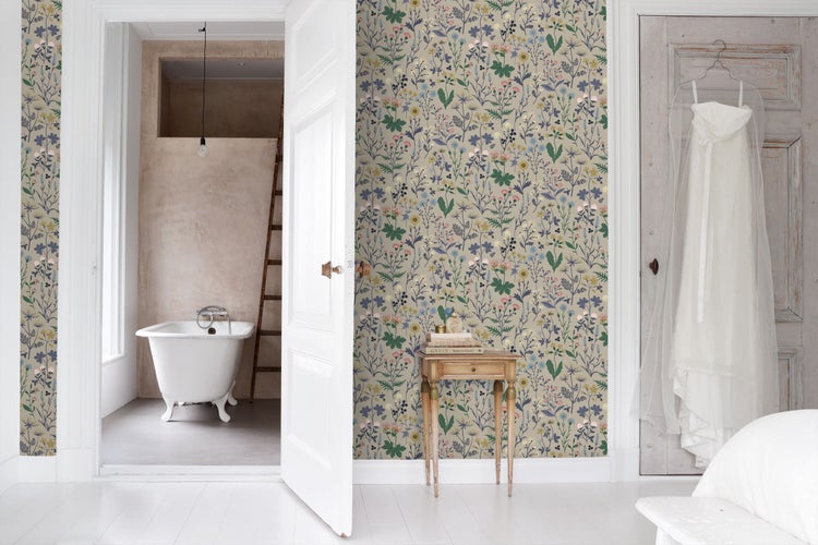 Vliestapete mit floralem Wildblumenmuster in einem hellen Zimmer mit Blick auf ein Badezimmer mit freistehender Badewanne und Holzleiter.