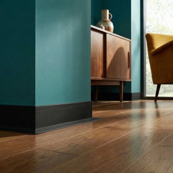 Wohnzimmer mit Parkettboden, dunkler Sockelleiste und gestrichener Wand in einer Einrichtung im modernen Stil mit Holzkommode.
