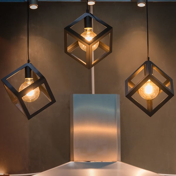 Rundes Badefass aus Holz mit Einstiegstreppe auf einer beleuchteten Holzterrasse mit Sofa, Laternen und Pflanzen im Garten bei Dämmerung.