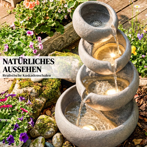 Vierstufiger Kaskadenbrunnen in Steinoptik mit integrierter Beleuchtung auf einer Terrasse neben einem Blumentopf.