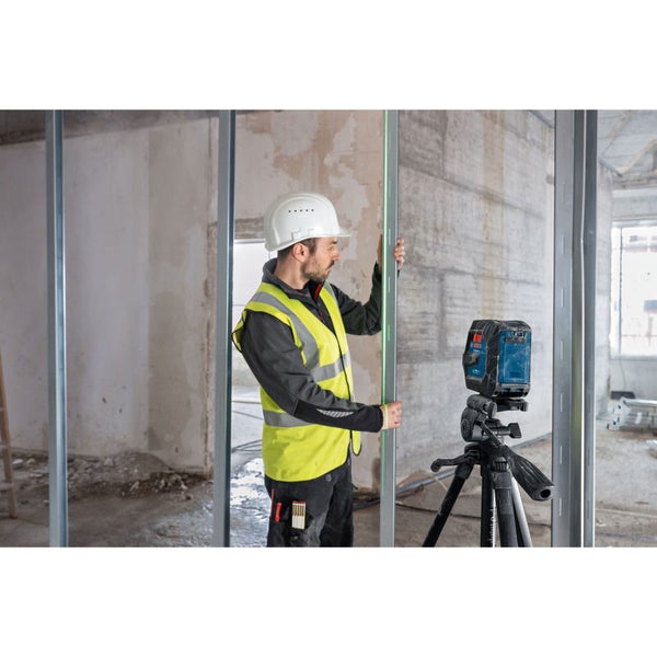 Ein Bauarbeiter benutzt einen Linienlaser zur Ausrichtung eines Metallständers an einer Baustelle.