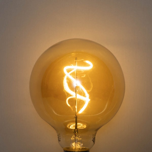 Eingeschaltete LED-Filament-Lampe in Globe-Form mit bernsteinfarbenem Glas und spiralförmigem Leuchtdraht.