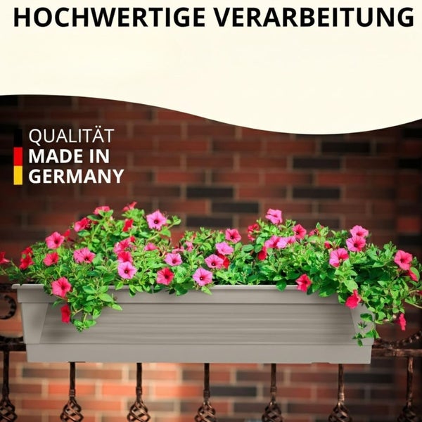 Ein rechteckiger Blumenkasten aus Kunststoff mit blühenden Blumen, montiert an einem Geländer vor einer Ziegelwand, mit Herkunftsnachweis.