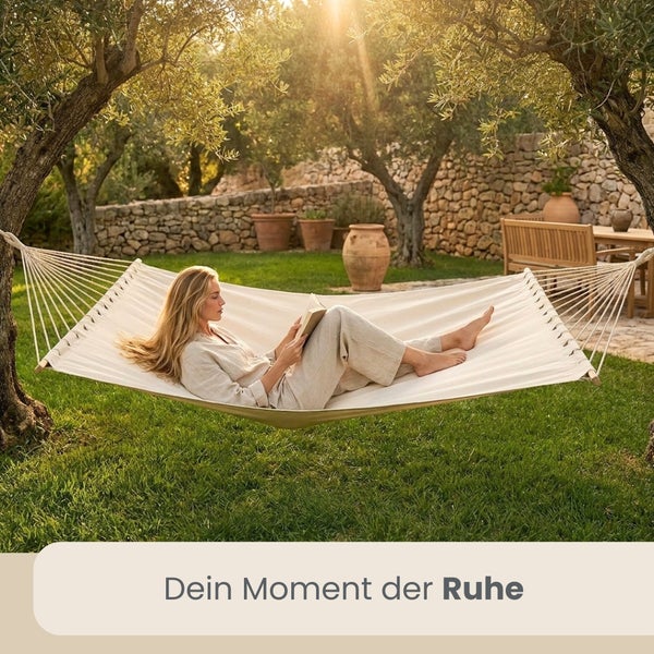 Eine Frau liest ein Buch in einer hellen Hängematte, die zwischen zwei Bäumen in einem sonnigen Garten befestigt ist.