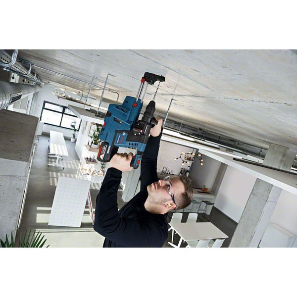 Ein Mann bohrt mit einem Bohrhammer in eine Decke in einem modern eingerichteten Raum.