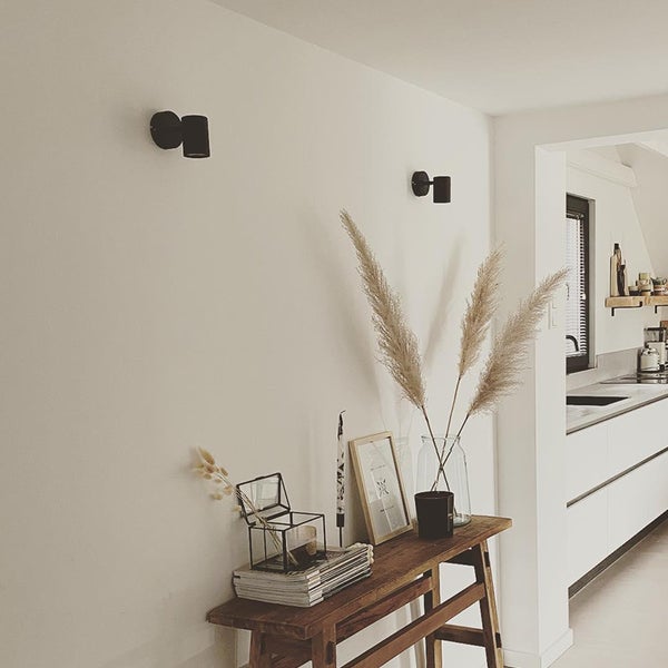 Einrichtungsbeispiel mit zwei Wandleuchten, einer Holzkonsole mit Dekoration und einer angrenzenden Küche