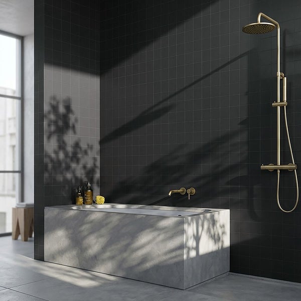 Modernes Badezimmer mit Badewanne in Betonoptik, dunklen Fliesen und messingfarbener Duscharmatur sowie Armaturen.